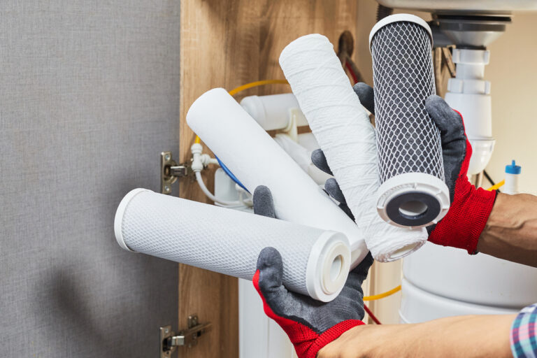 Water filter cartridge in human hand. Plumber hands holding cartridge for replace a water filter at kitchen. Fix purification osmosis system.