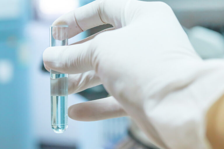 A person wearing a white glove holding a test tube during water testing